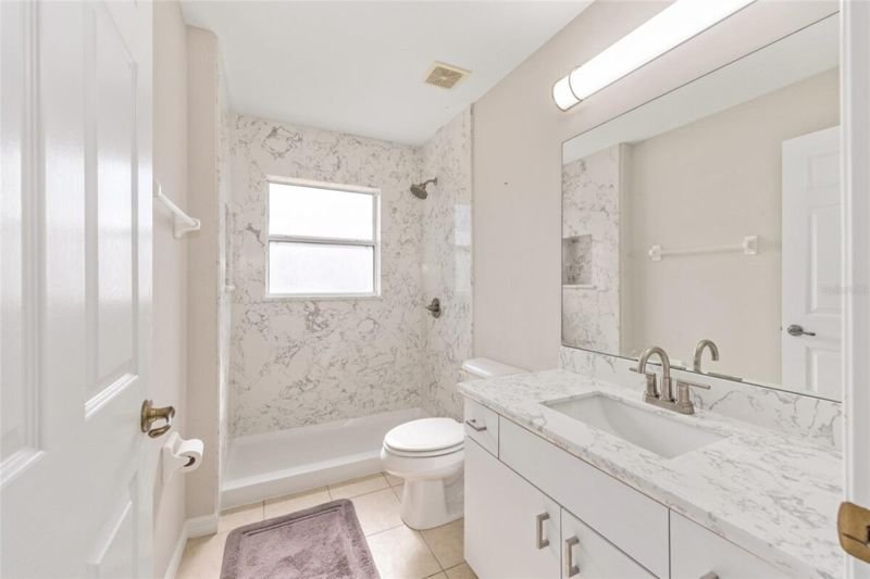 Renovated guest bathroom with marble tub and shower